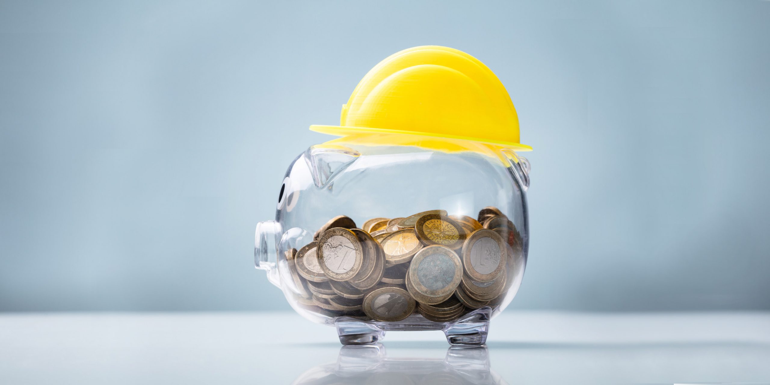 Construction hat sitting on top of glass piggy bank